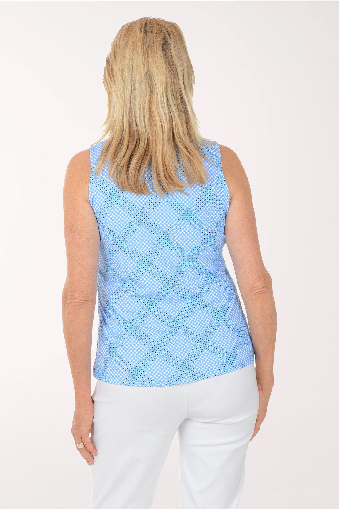 Woman wearing a light blue sleeveless checkered top and white pants on a white background