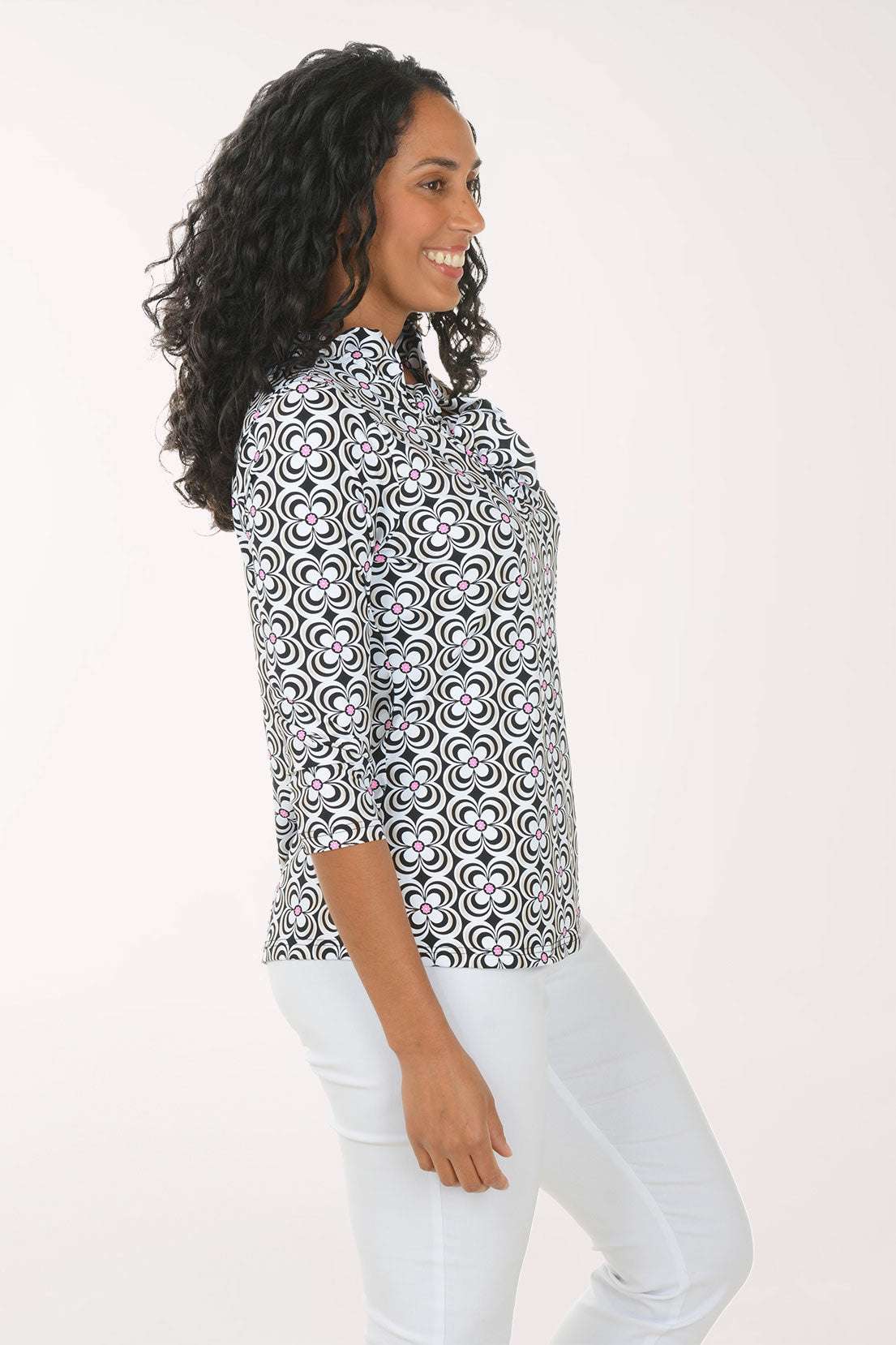 Woman wearing a patterned blouse and white pants on a white background