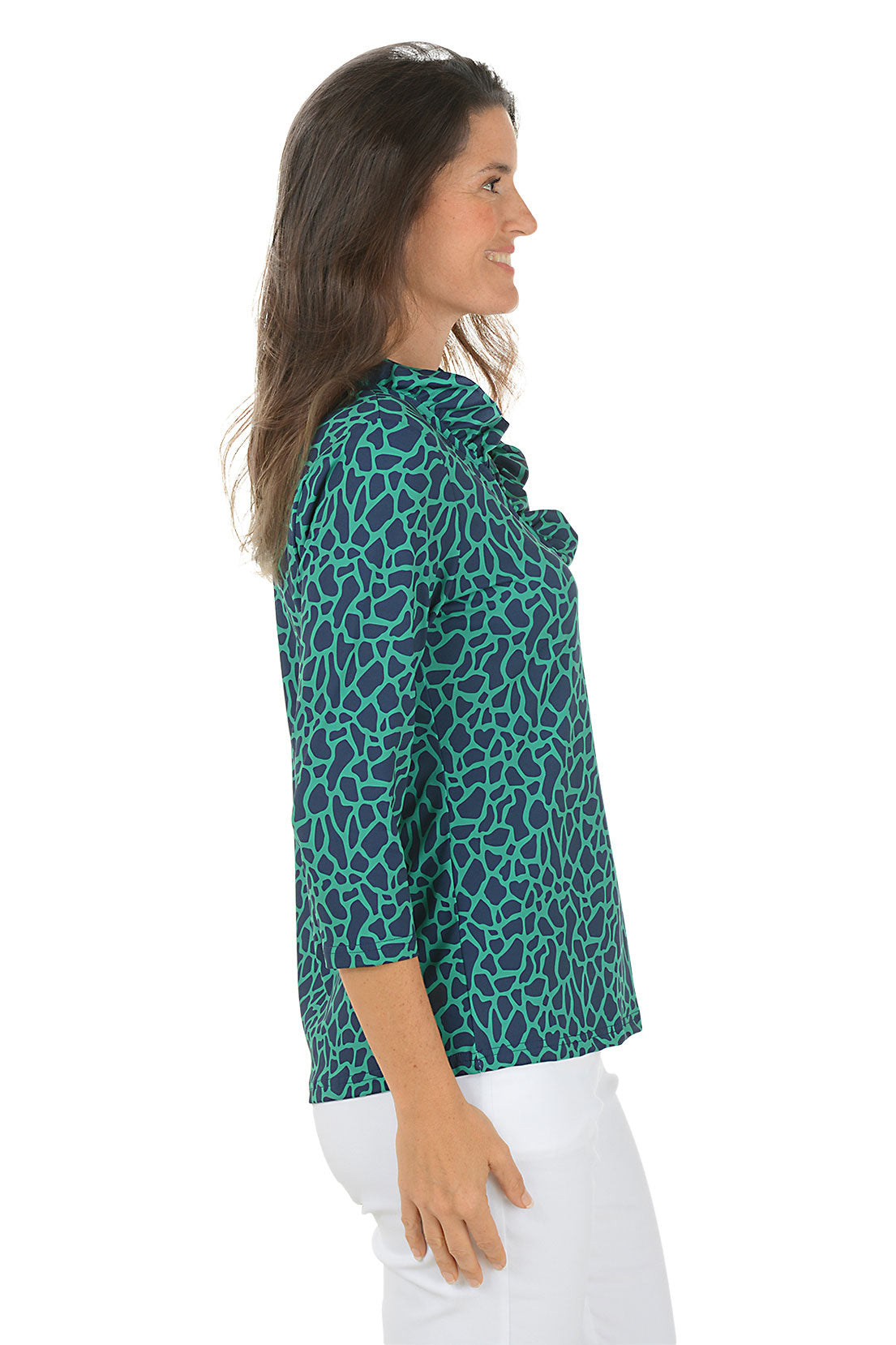 Woman wearing a teal leopard print shirt and white pants on a white background. Side shot.