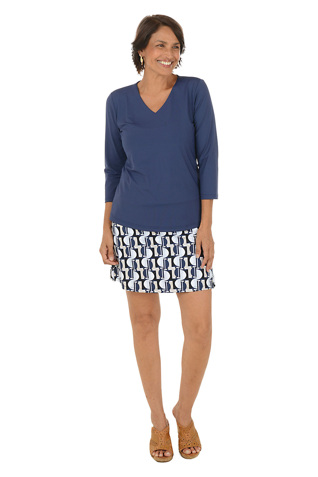 Woman wearing a blue top and patterned skirt on a white background.