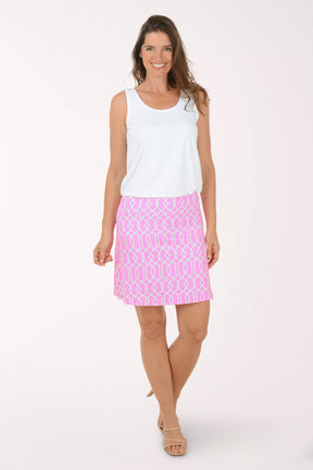 Woman wearing a white sleeveless top and pink patterned skirt on a white background