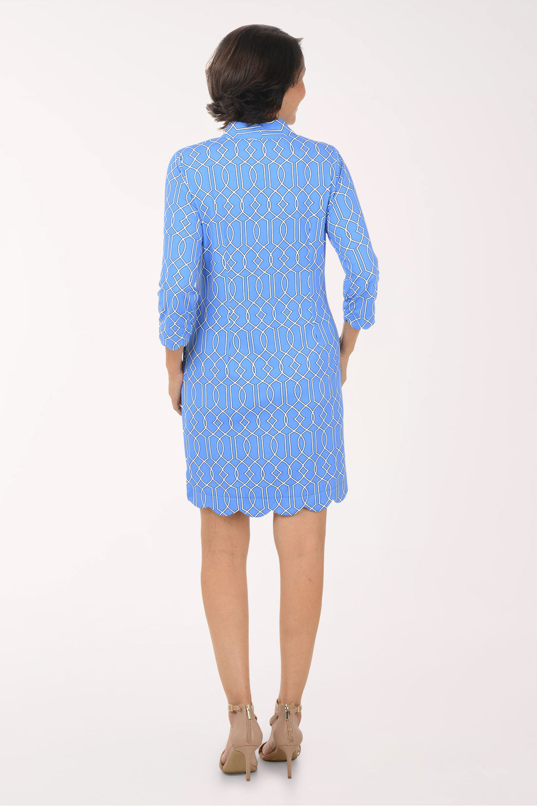 Woman wearing a blue dress with a white geometric pattern on a white background