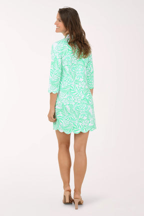 Woman wearing a green patterned dress on a white background. Back shot.