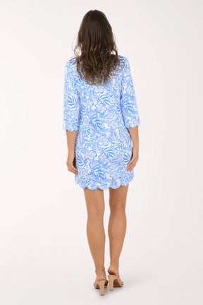 Woman wearing a blue patterned dress on a white background. Back shot.
