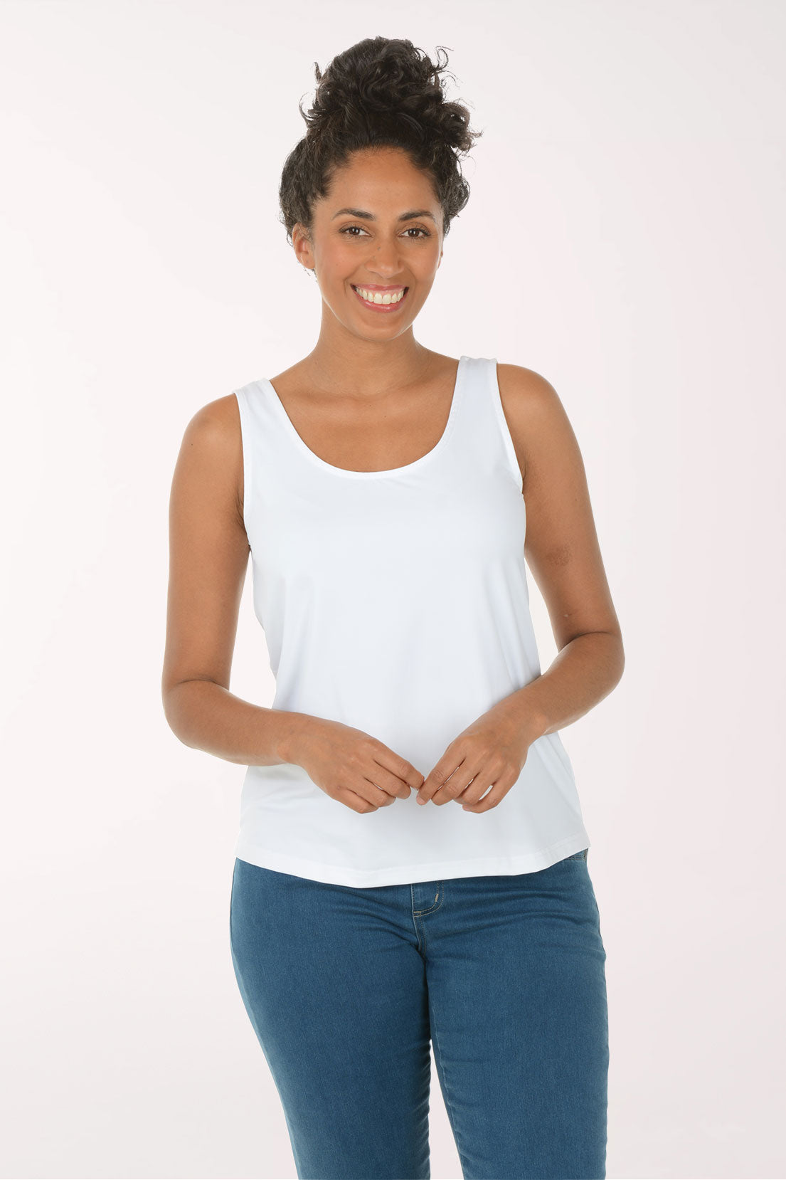 Woman wearing a white tank top and blue jeans on a white background
