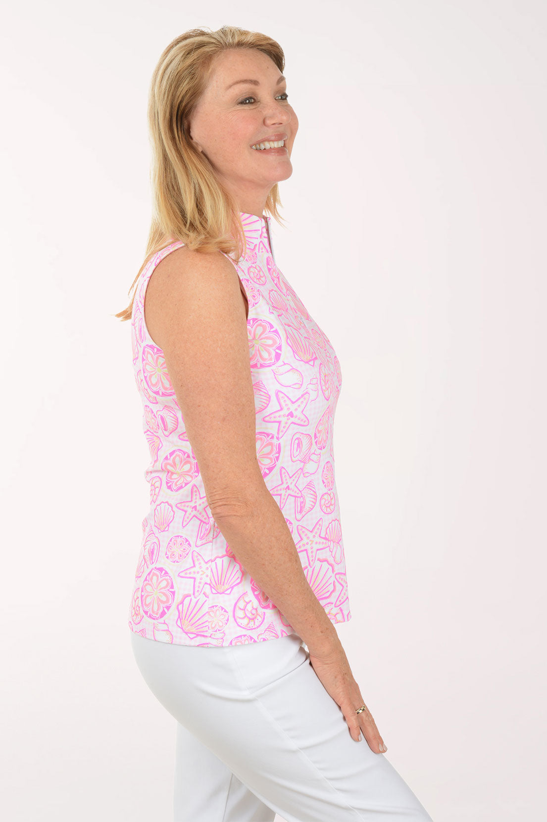Woman wearing a pink sleeveless top with shell pattern on a white background