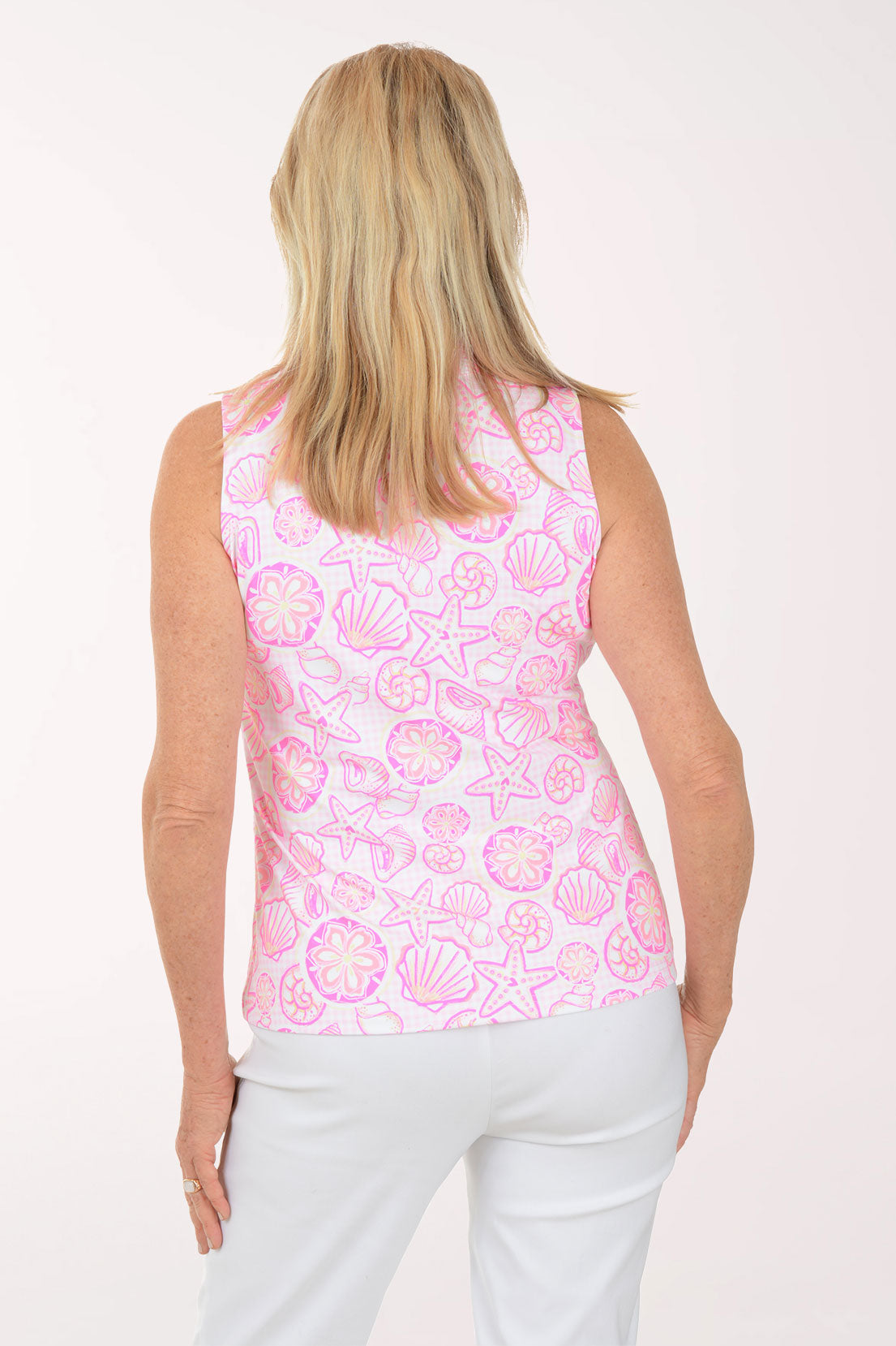 Woman wearing a pink sleeveless top with shell pattern on a white background