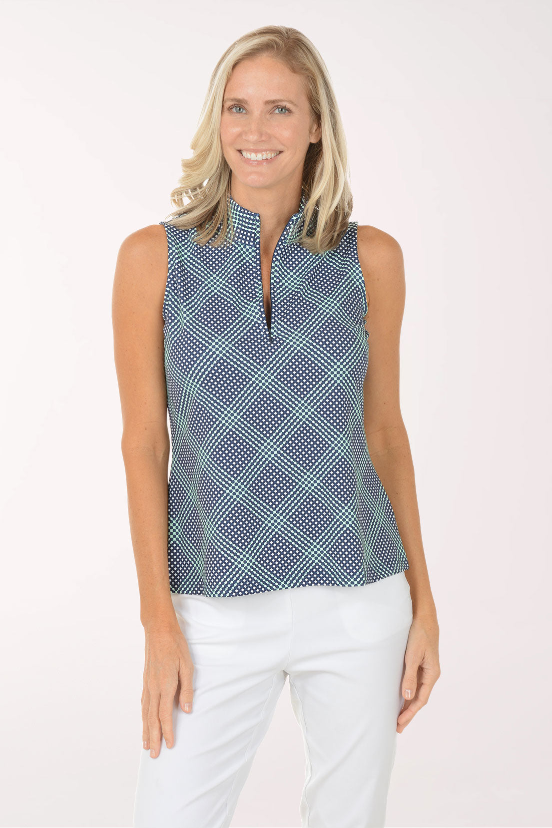 Woman wearing a sleeveless patterned top and white pants on a white background