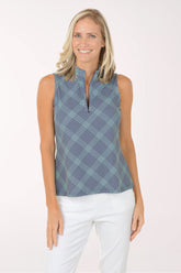 Woman wearing a sleeveless patterned top and white pants on a white background