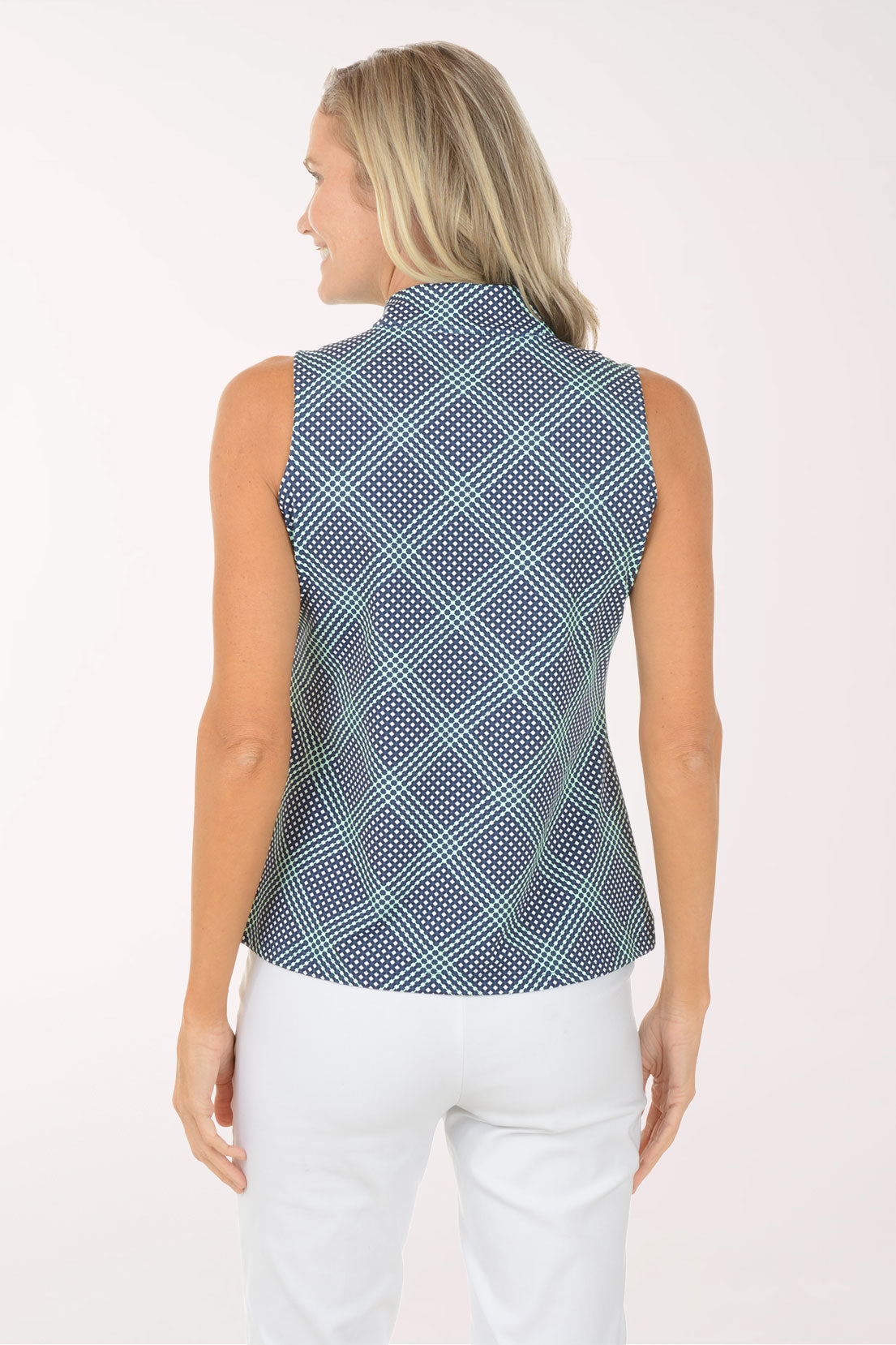 Woman wearing a sleeveless patterned top and white pants on a white background