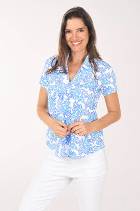 Woman wearing a blue floral blouse and white pants on a white background