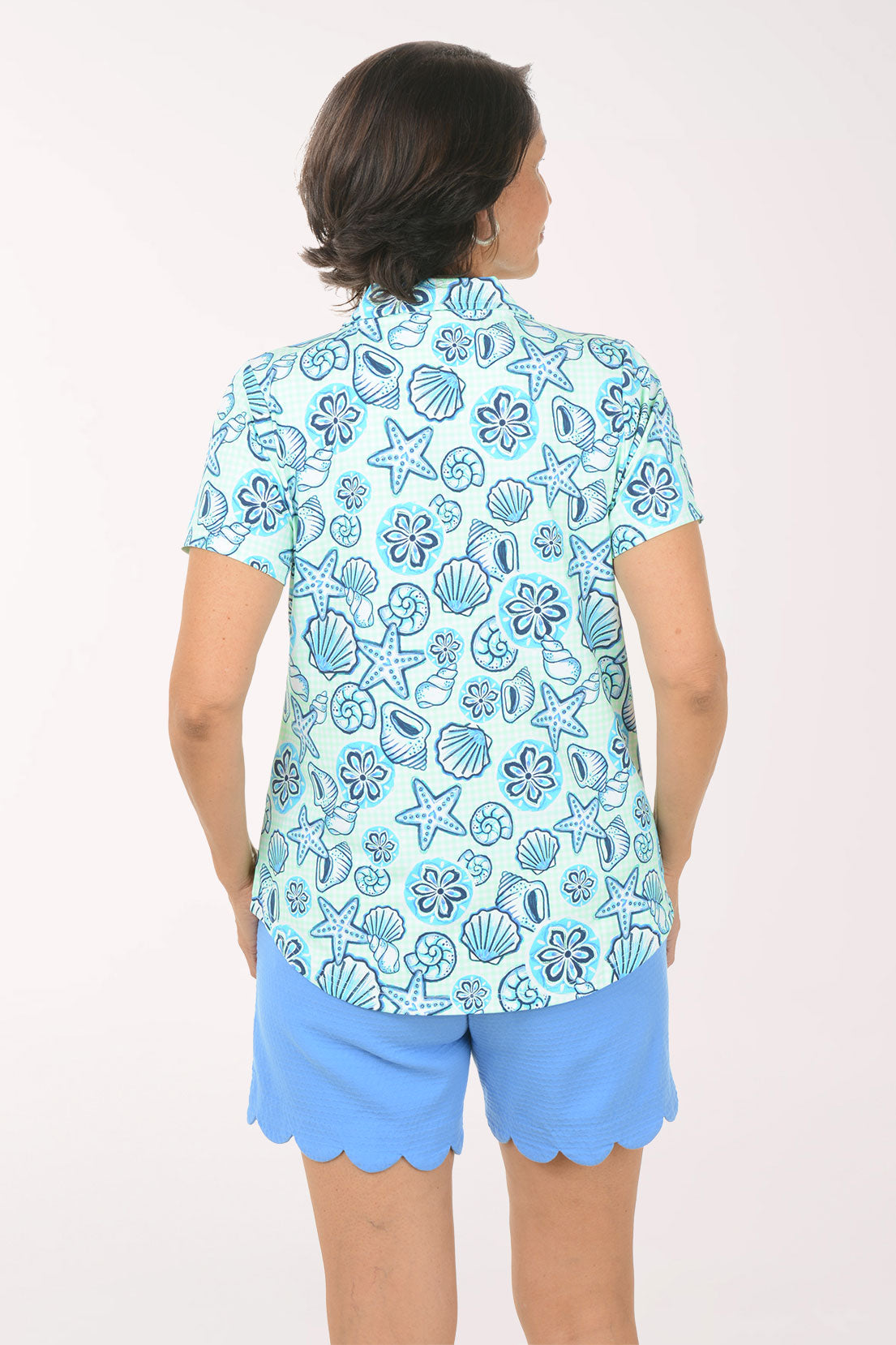 Woman wearing a blue floral patterned shirt and matching shorts on a white background