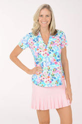 Woman wearing a colorful floral blouse and pink skirt on a white background