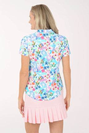 Woman wearing a colorful floral blouse and pink skirt on a white background