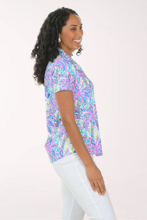 Woman wearing a colorful patterned blouse against a white background
