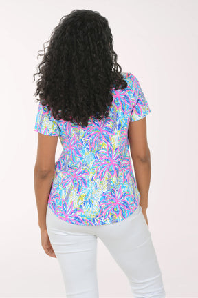 Woman wearing a colorful patterned blouse against a white background