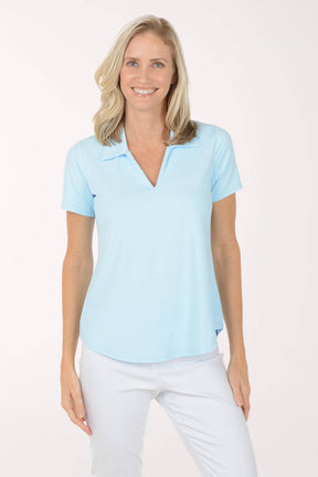 Woman wearing a light blue polo shirt and white pants on a white background