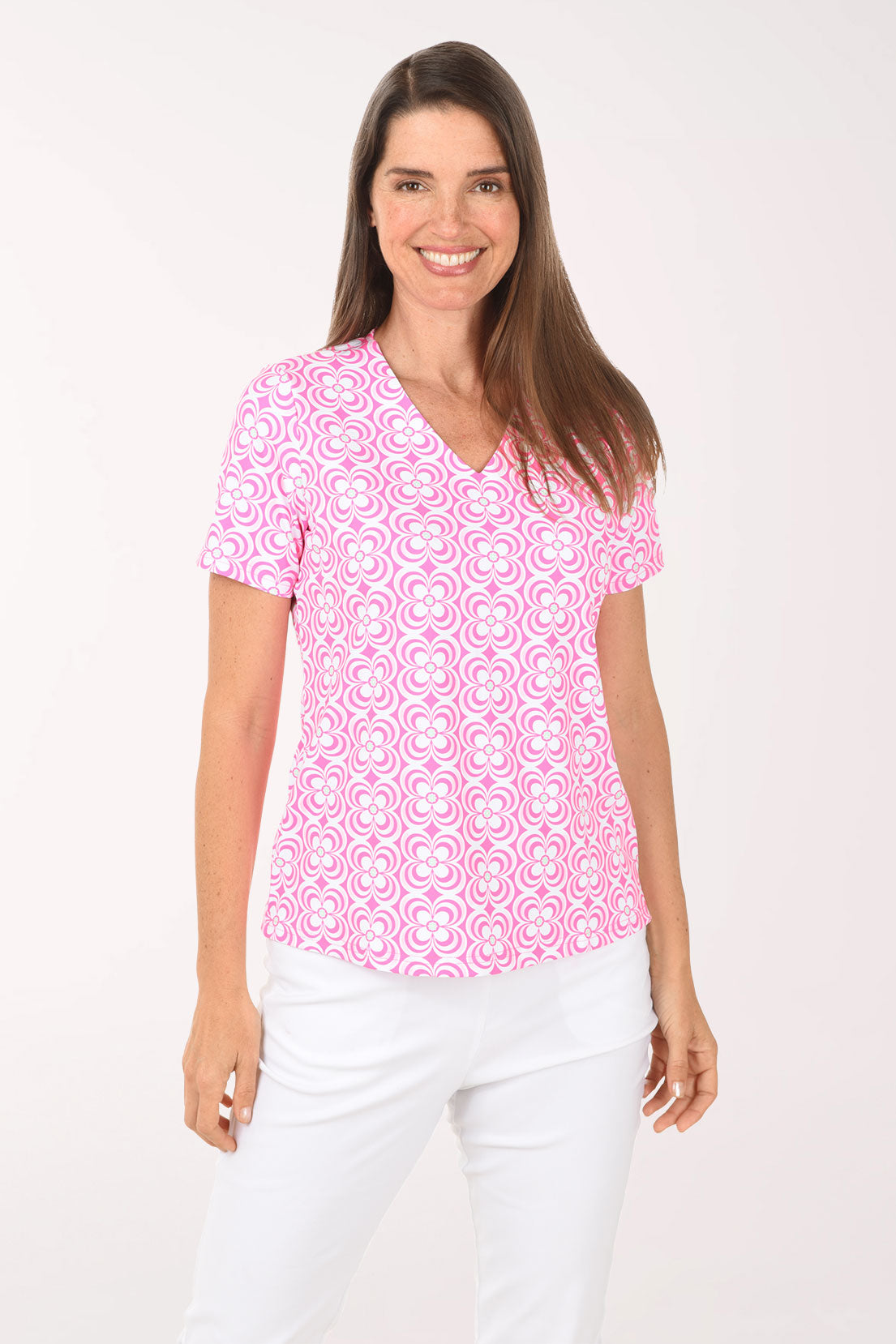 Woman wearing a pink patterned top and white pants on a white background