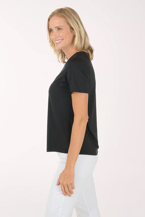 Woman wearing a black t-shirt and white pants on a white background