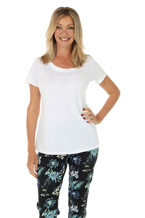 Woman wearing a white top and floral pants on a white background