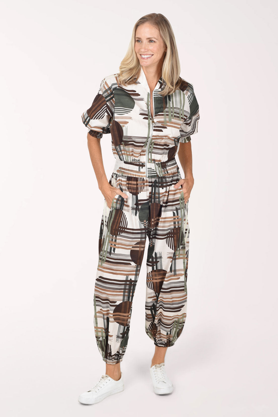 Woman wearing camouflage plaid patterned ankle length joggers with contrast stripes on side leg.