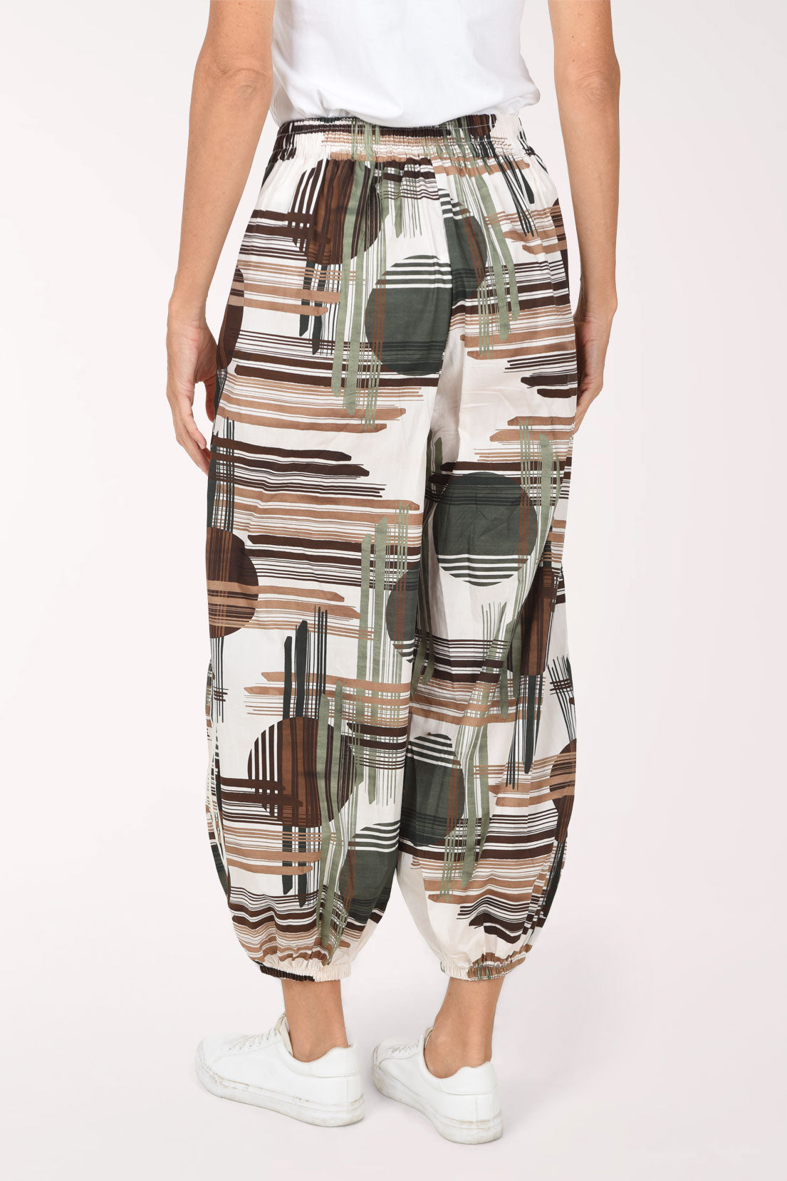 Woman wearing camouflage plaid patterned ankle length joggers with contrast stripes on side leg.