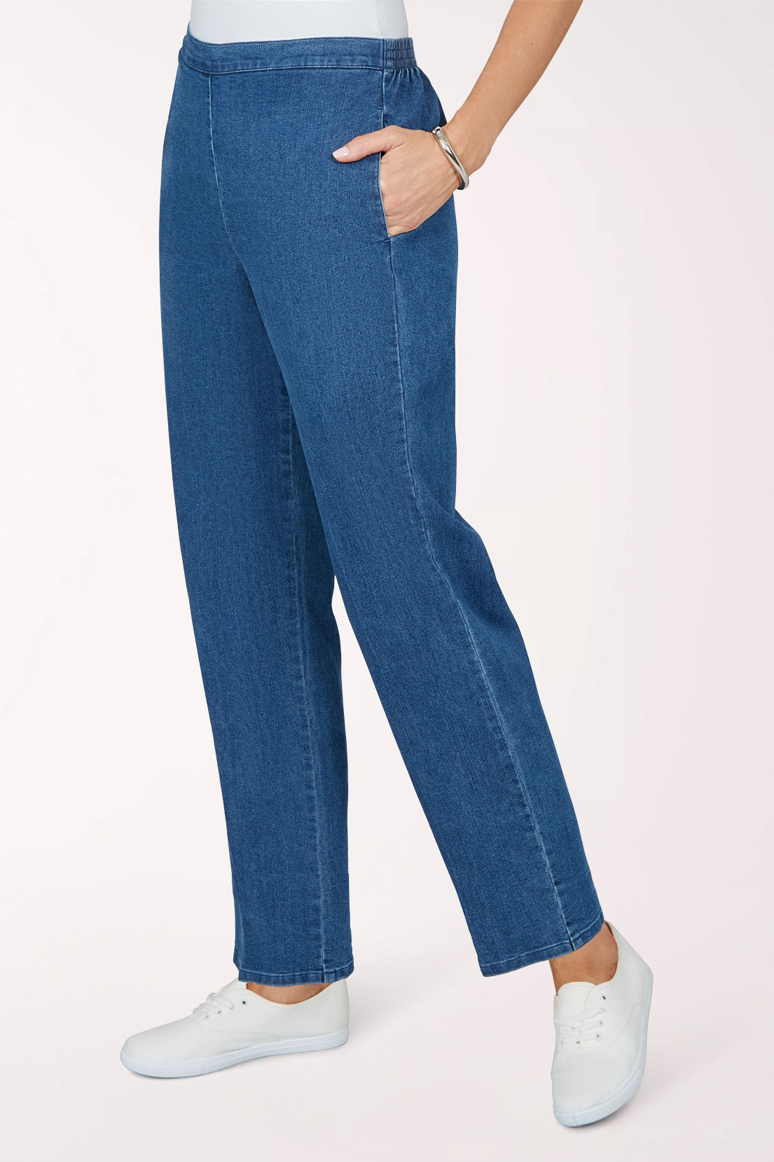 Three-quarter view of the medium indigo medium length denim pants with one hand in the side seam pocket.