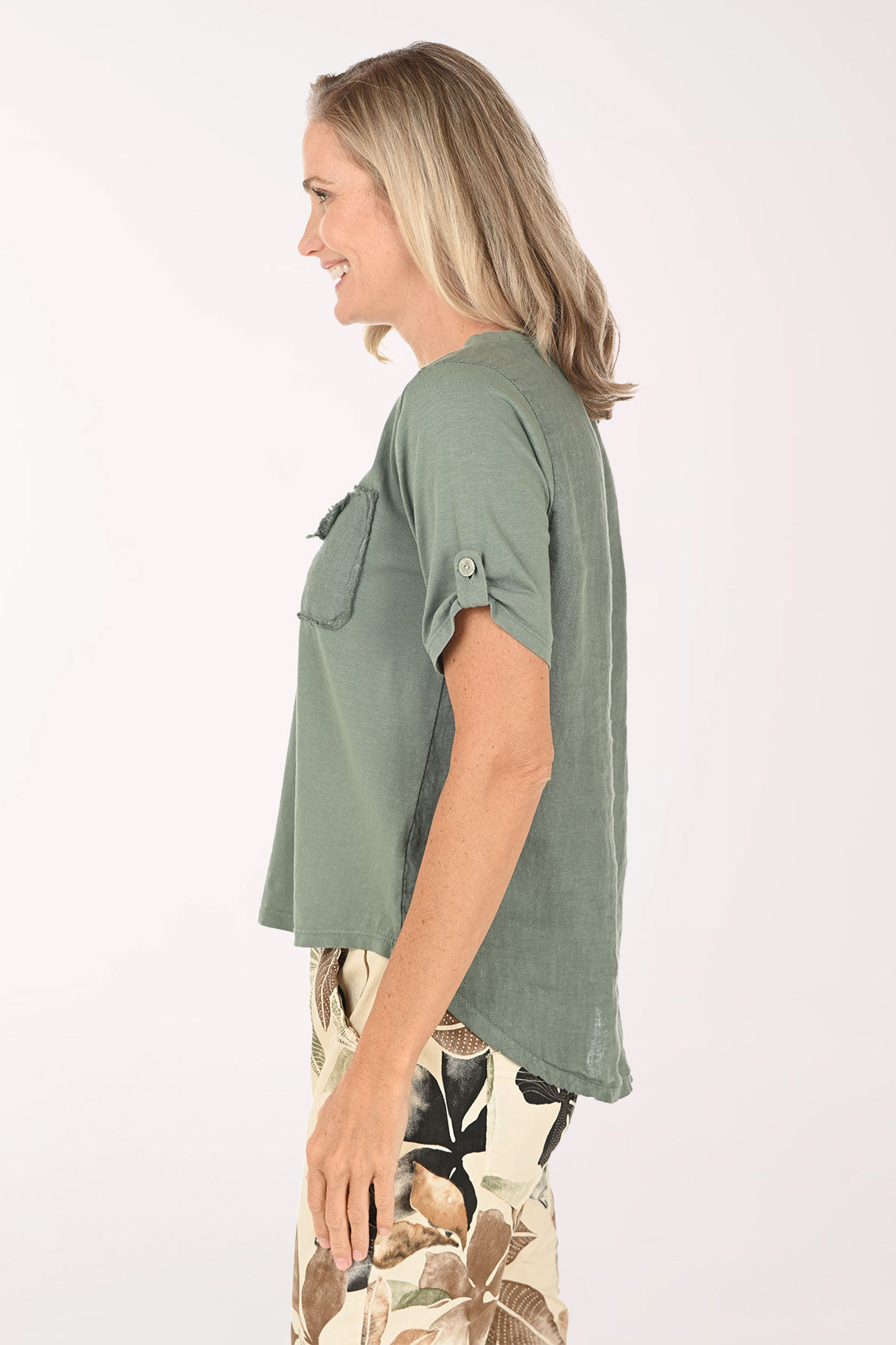 Woman wearing a green t-shirt with a pocket and floral pants on a white background