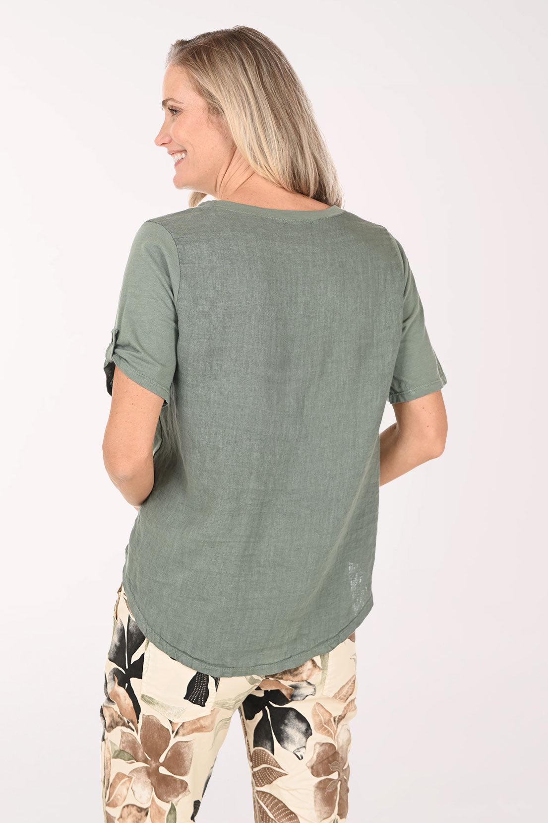 Woman wearing a green t-shirt with a pocket and floral pants on a white background