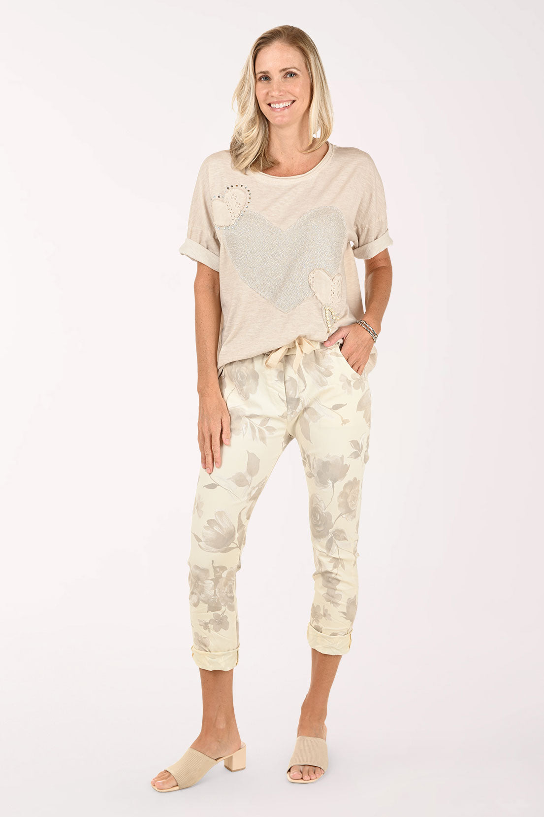 Woman wearing a beige top and patterned pants on a white background