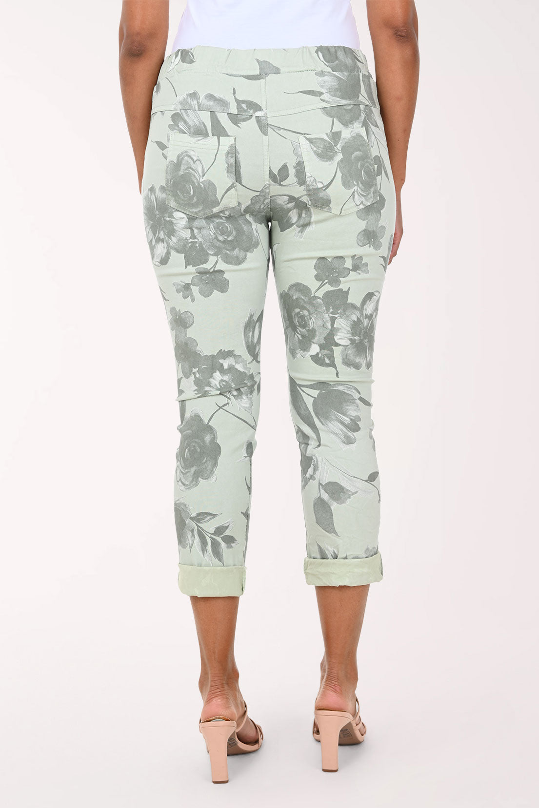 Person wearing light green floral pants on a white background