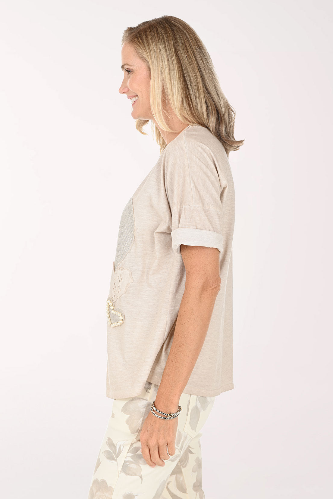 Woman wearing a beige top and light-colored pants on a white background