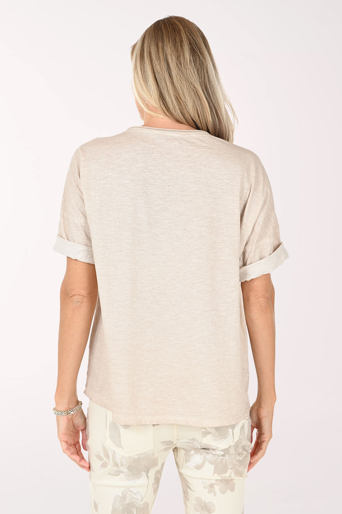 Woman wearing a beige top and light-colored pants on a white background