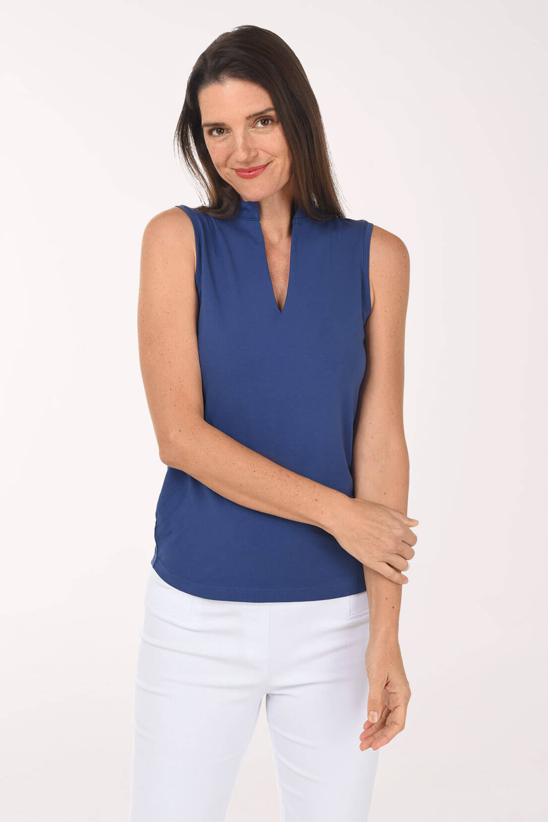 Woman wearing a blue sleeveless top and white pants on a white background