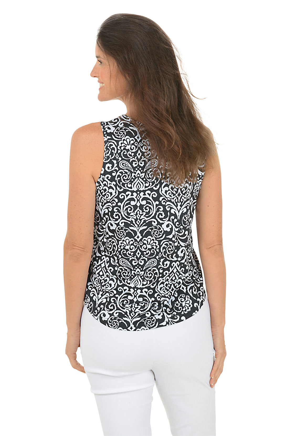 Woman wearing a black and white patterned sleeveless top with white pants on a white background