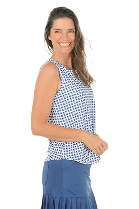 Woman wearing a sleeveless patterned top and blue skirt on a white background