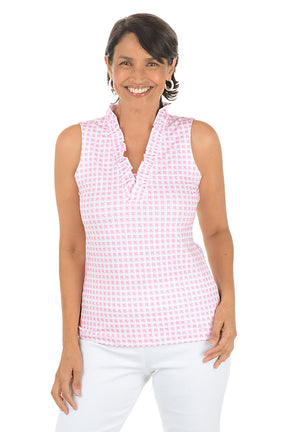 Woman wearing a pink checkered sleeveless top and white pants on a white background