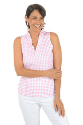 Woman wearing a pink checkered sleeveless top and white pants on a white background