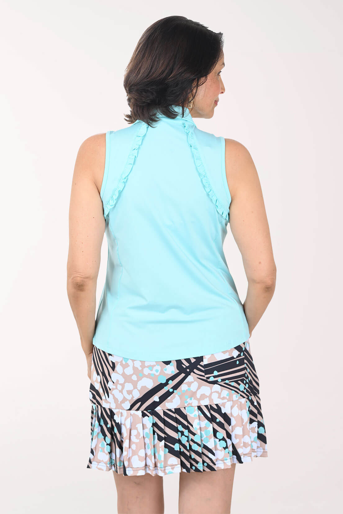 Woman wearing a light blue sleeveless top with ruffles and a patterned skirt on a white background - back shot