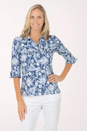 Woman wearing a blue floral blouse with white pants on a white background