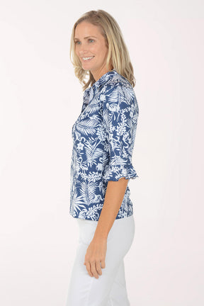 Woman wearing a blue floral blouse with white pants on a white background