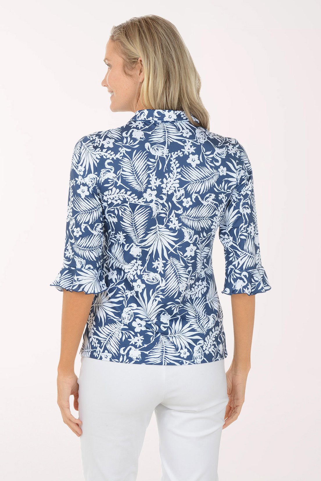 Woman wearing a blue floral blouse with white pants on a white background