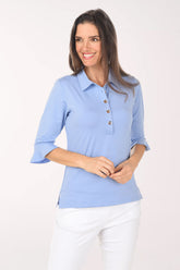 Woman wearing a light blue polo shirt with rolled-up sleeves on a white background
