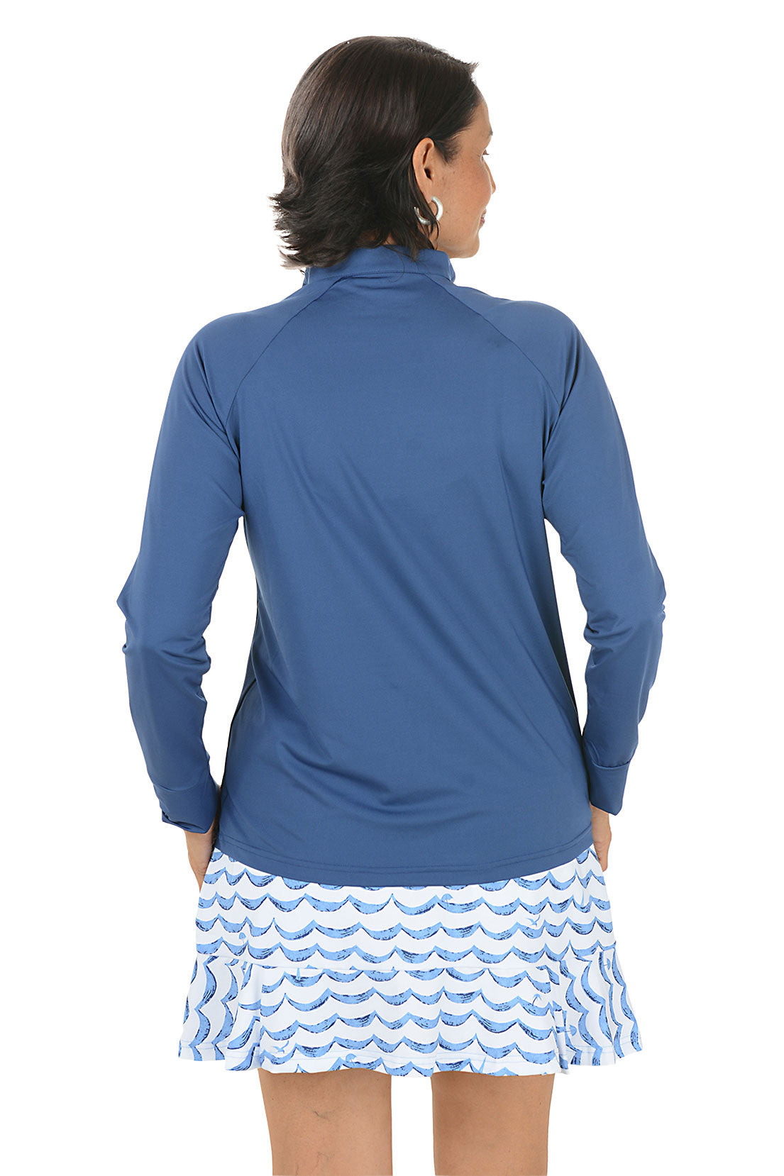 Woman wearing a blue long-sleeve top with a zipper, standing against a white background. Back shot.