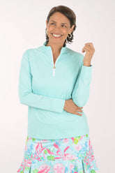 Woman wearing a light blue long-sleeve top and colorful floral skirt on a white background