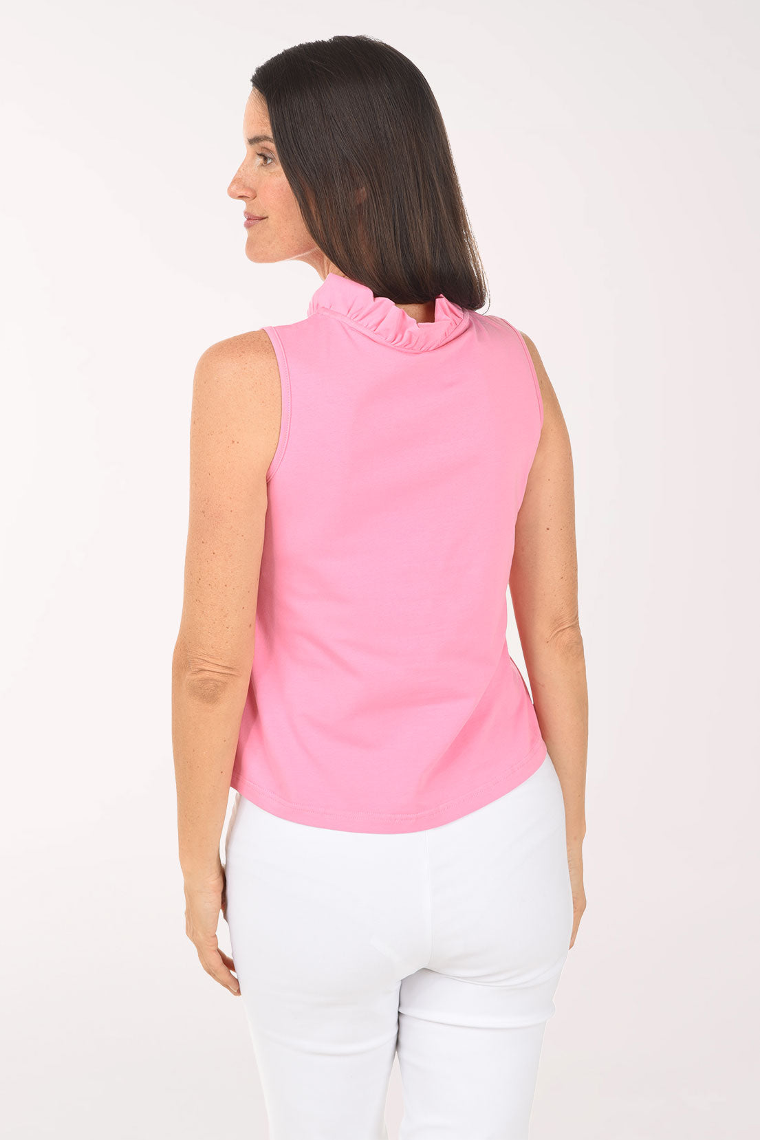 Woman wearing a pink sleeveless top and white pants on a white background
