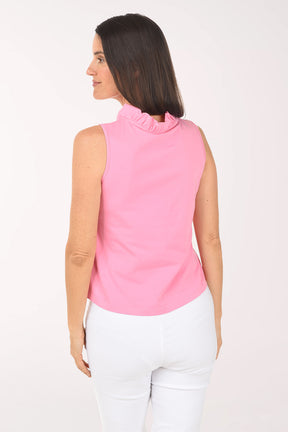 Woman wearing a pink sleeveless top and white pants on a white background
