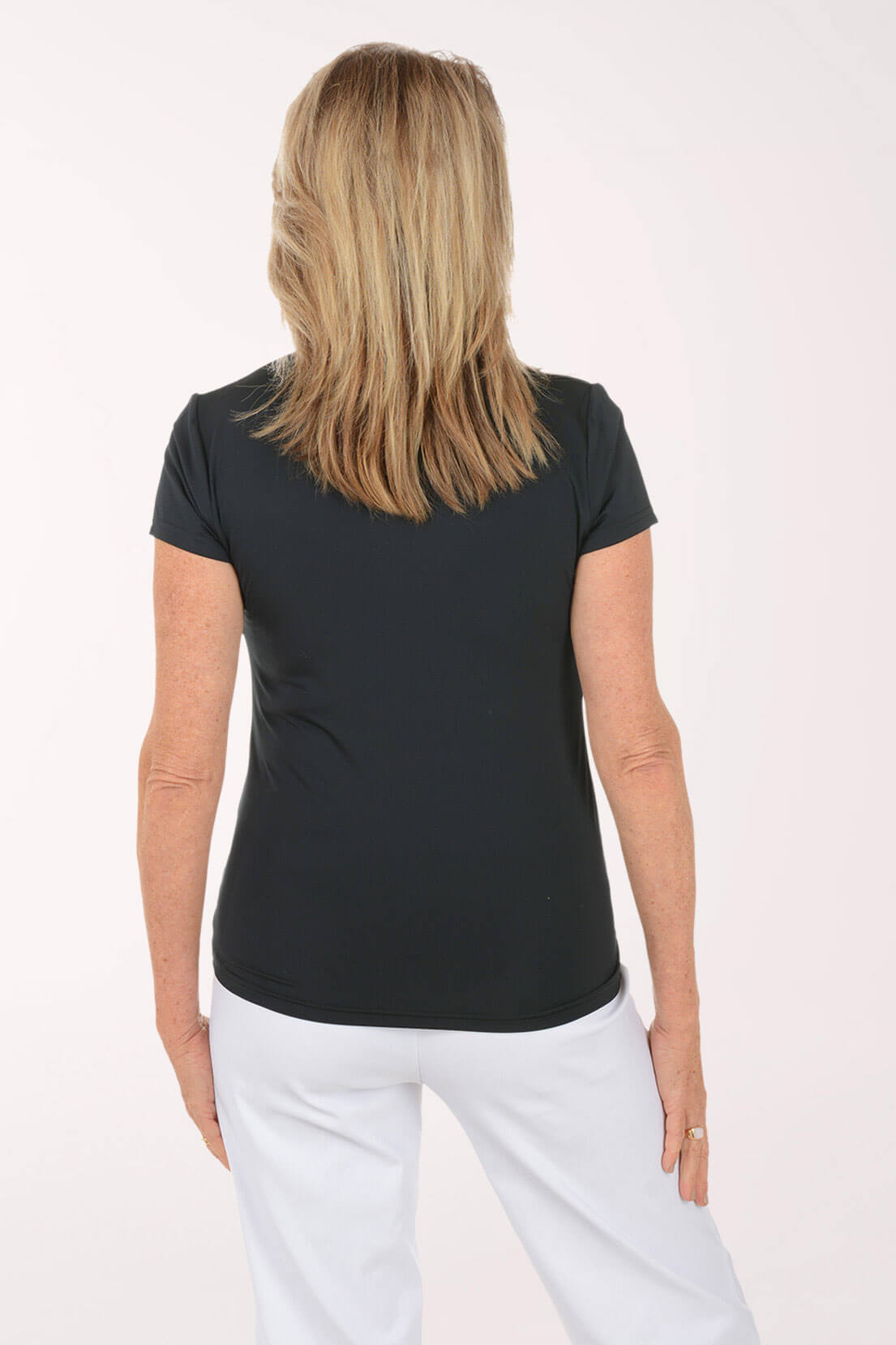 Woman wearing a black top and white pants on a white background