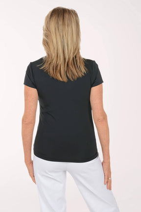 Woman wearing a black top and white pants on a white background