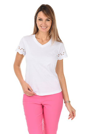 A woman wearing a white short-sleeved t-shirt with eyelet scallop detailing on the sleeves, paired with pink pants.